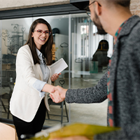 A woman shaking hands, greeting a man at work.